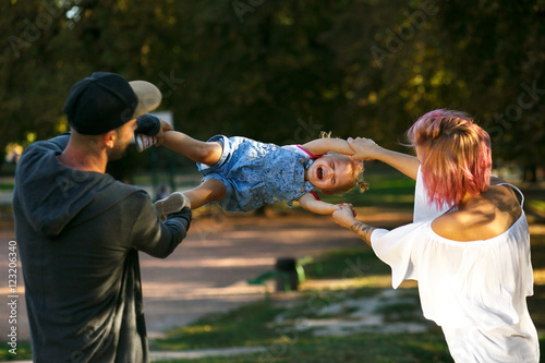 Mom and dad whirl their happy little daughter photo