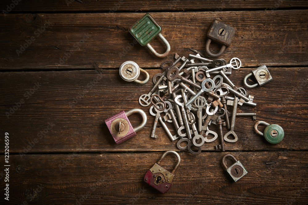 Group of old rusty padlocks with pile of keys on brown wooden table
Group of old rusty padlocks with pile of keys on brown wooden table