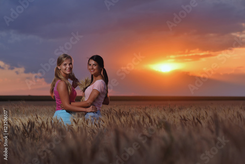 Girls feeling free in a beautiful natural setting in wheat field at sunset