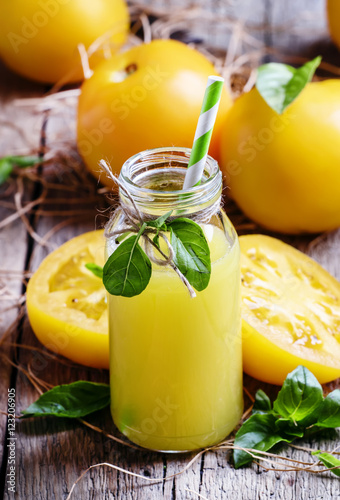 Freshly squeezed juice of yellow tomatoes with basil in a glass