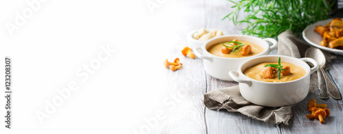Soup with chanterelles and herbs, white wooden table