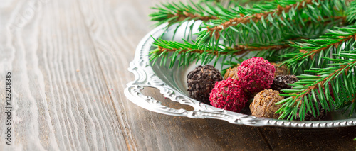 Assorted dark chocolate truffles with dried strawberry pieces and chopped hazelnuts on rustic wooden background, selective focus. Christmas Holiday time