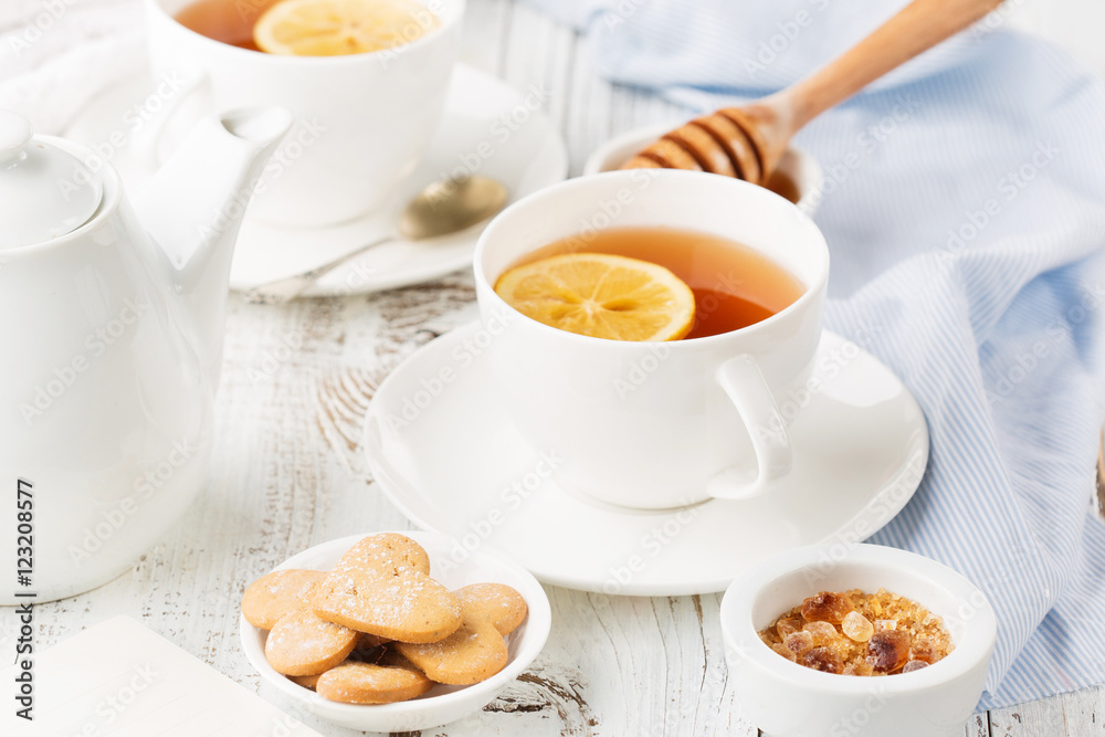 Cups of hot black tea, lemon and honey on white rustic wooden background. Breakfast concept. Selective focus Cups of hot black tea, lemon and honey on white rustic wooden background. Breakfast concept. Selective focus