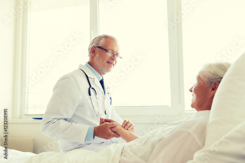 doctor checking senior woman pulse at hospital