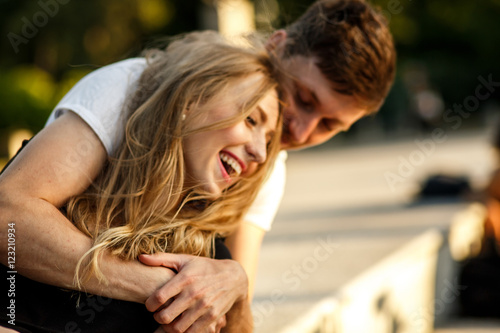 Charming lady laughs while she sits in man's embraces