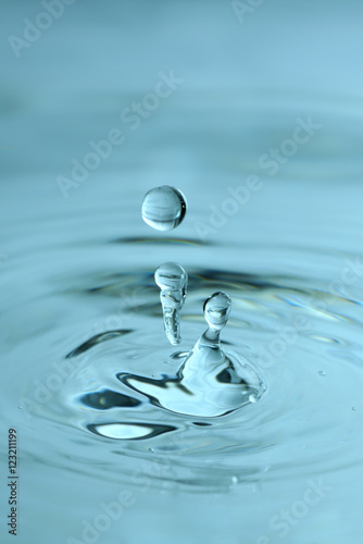 Beautiful splash of water drop. Freeze action. High-speed shooting of water drop. Beautiful drops of stop time, water splashing close up. Crystal clear water waves, drops and sprays. Blue water