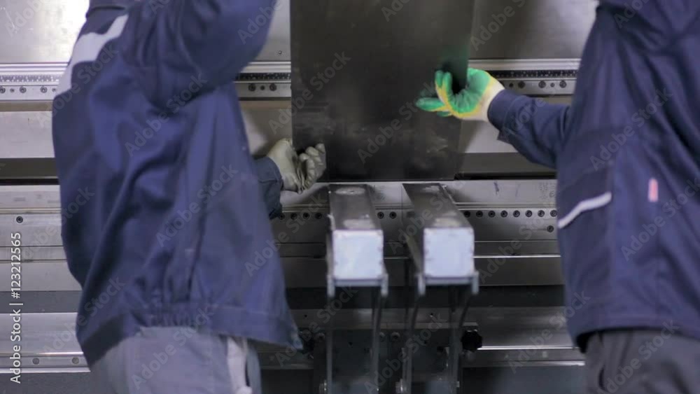 Worker hands bend metal sheet on a modern bending industrial machine at a factory. HD. Worker hands bend metal sheet on a modern bending industrial machine at a factory. HD.