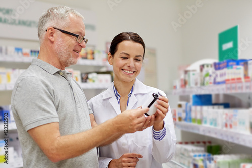 pharmacist showing drug to senior man at pharmacy photo