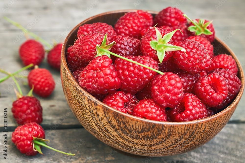Fresh raspberries in wooden bowl on grey rustic wooden background Fresh raspberries in wooden bowl on grey rustic wooden background