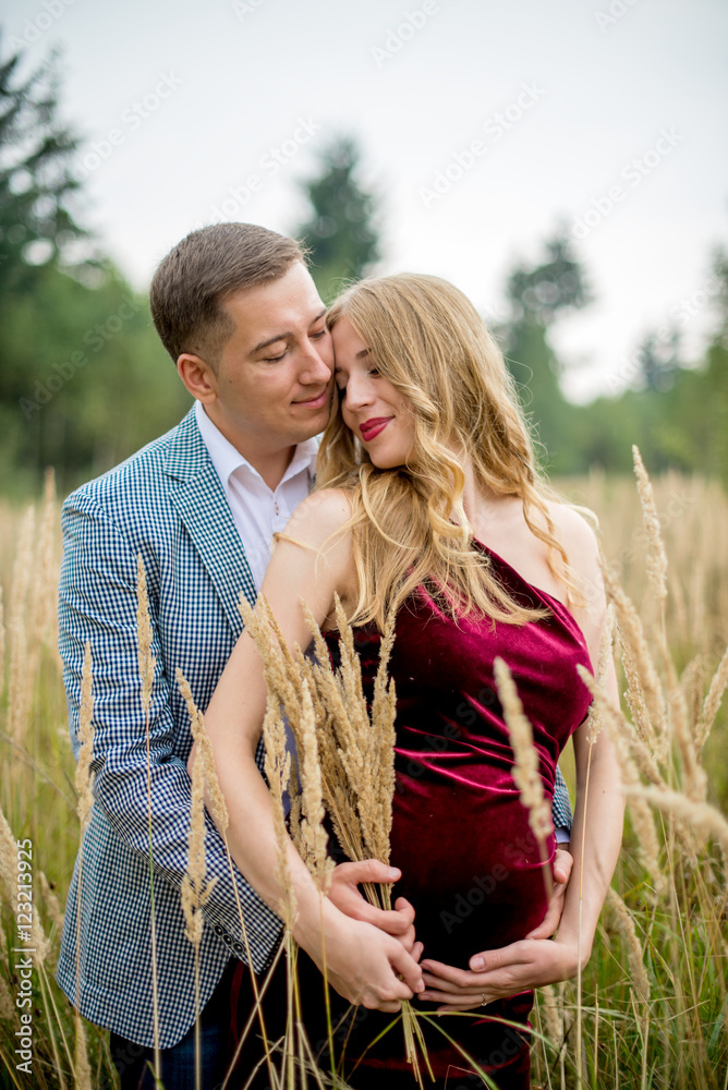 Portrait of a happy pregnant couple in tall grass