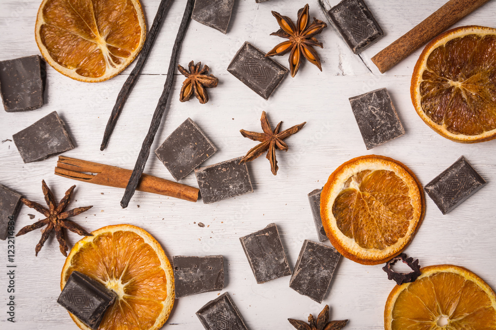 chocolate with cinnamon, orange and vanilla on white wooden table chocolate with cinnamon, orange and vanilla on white wooden table
