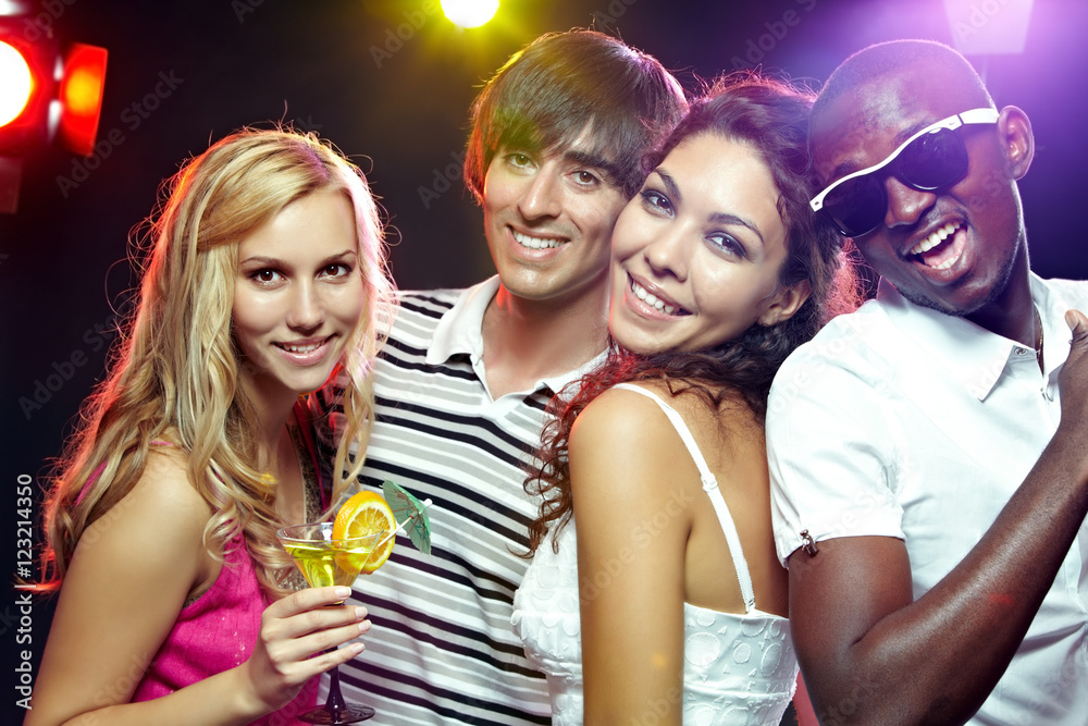 Portrait of four friends at club looking at camera and smiling