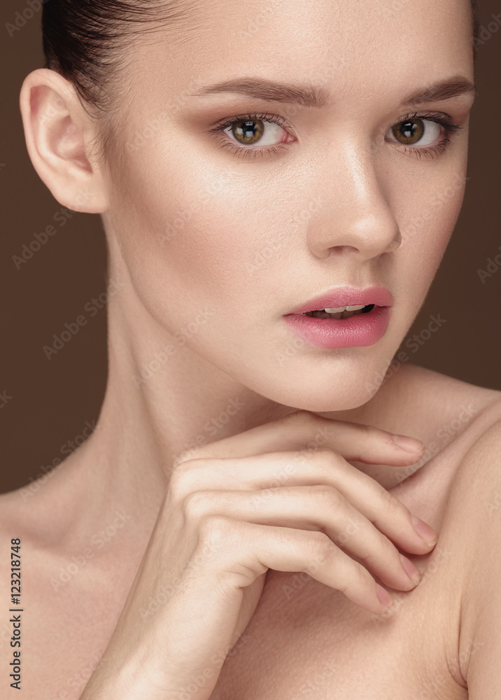 Beautiful Young Woman with clean fresh skin close up over beige Beautiful Young Woman with clean fresh skin close up over beige