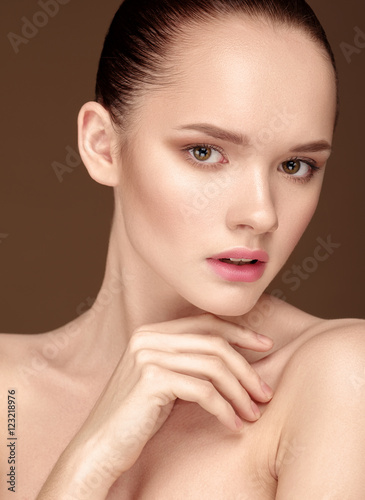 Beautiful Young Woman with clean fresh skin close up over beige