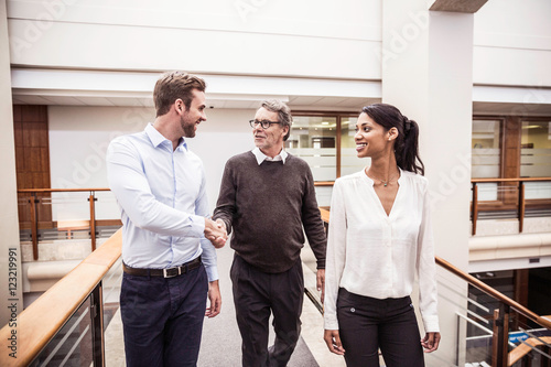 Senior businessman shaking hands with client on office walkway