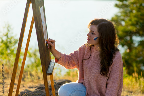 young artist draws a seascape at sunset photo