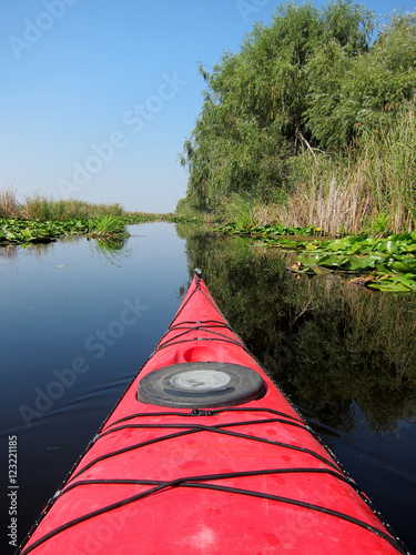 Nose of the red kayak on the background of wild nature. Kayaking in wildlife