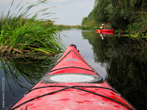 Nose of the red kayak on the background of wild nature. Kayaking