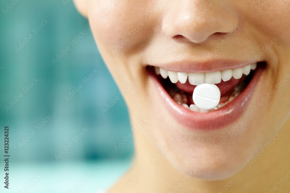 Fototapeta premium Female teeth holding a pill