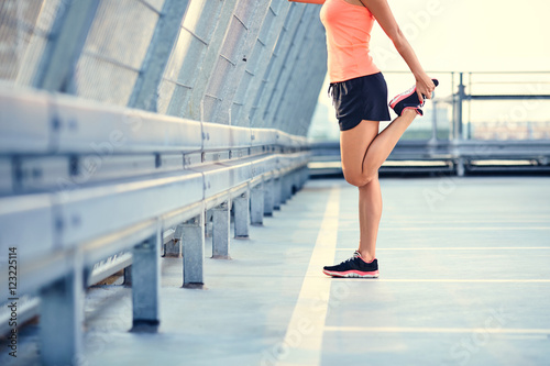 Closeup of woman stretching legs before running in city