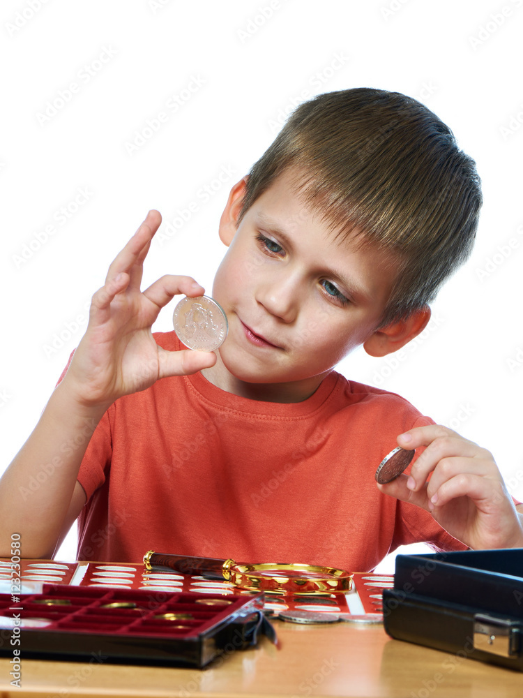 Fotografie Boy examines coins from his collection isolated