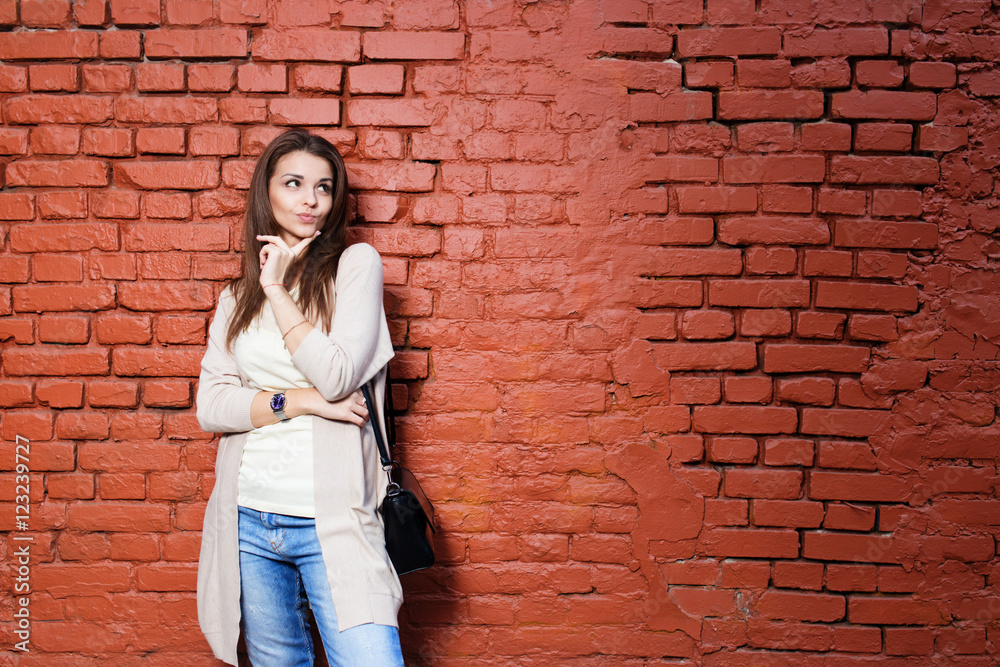 Young beautiful happy woman in casual cloths against brick wall