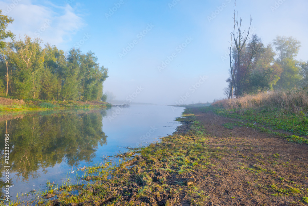 Shore of a foggy lake at sunrise in autumn