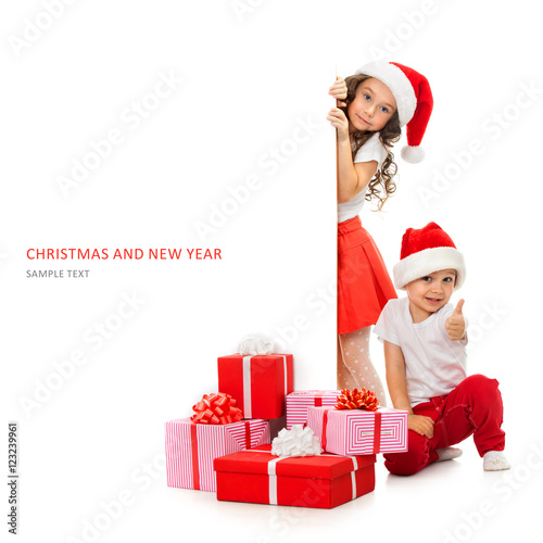 Kids in Santa hat peeking from behind blank sign billboard