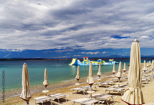 Fototapeta Naklejka Na Ścianę i Meble -  Empty sea beach with closed sun-umbrellas, Croatia, stormy weath