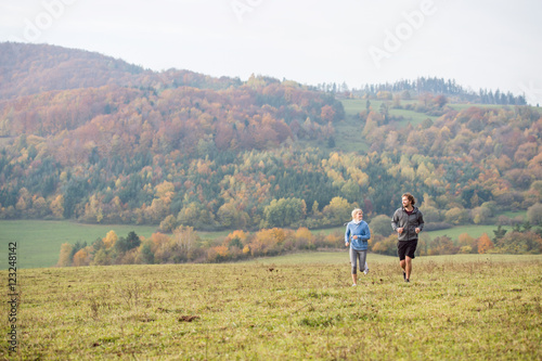 Beautiful young couple running in sunny autumn nature.