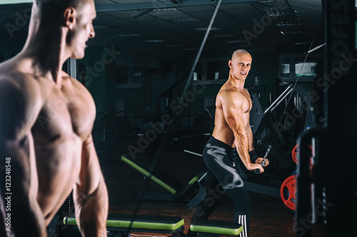 man exercising in trainer for triceps muscles in the gym