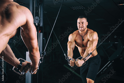 Bodybuider demonstrate crossover exercises in the gym.