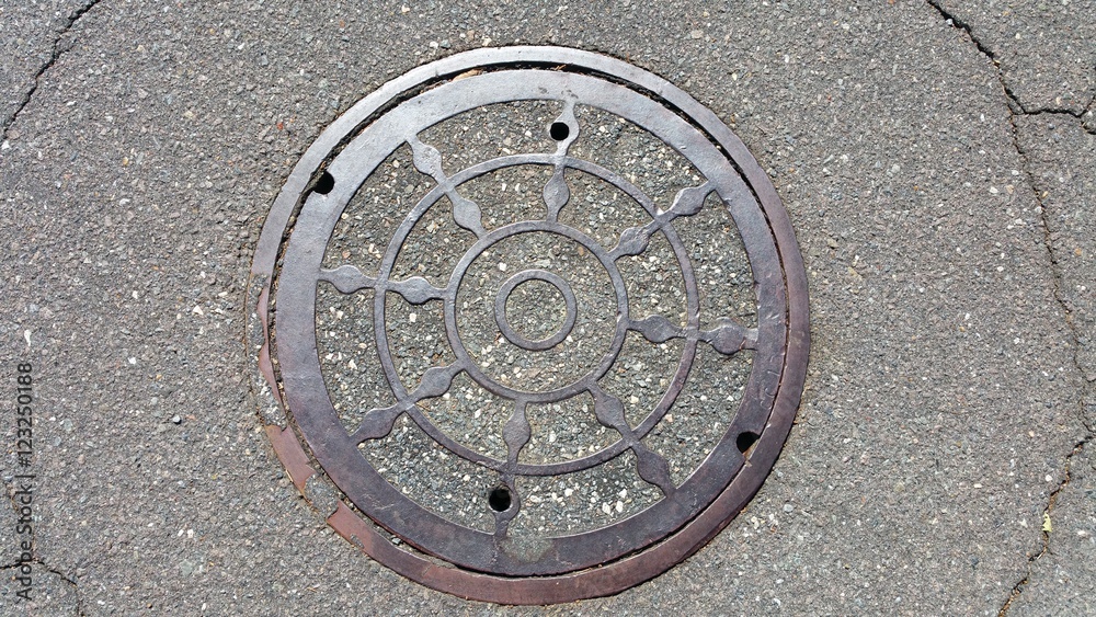 Old Manhole Cover and Cracked Asphalt