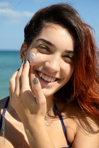 beautiful girl apply sunscreen on the beach