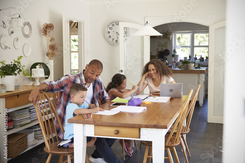 Parents Helping Children With Homework At Table