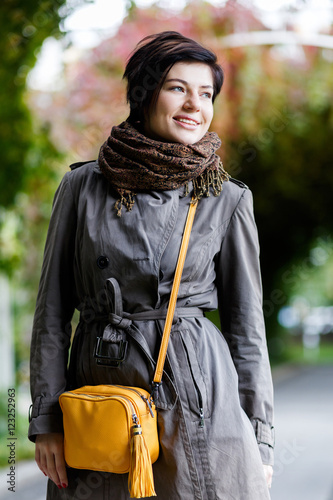 Smiling young brunette woman in warm clothes on autumn day