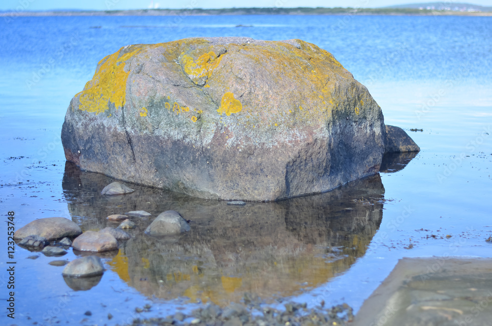 rock reflecting in silence blue water