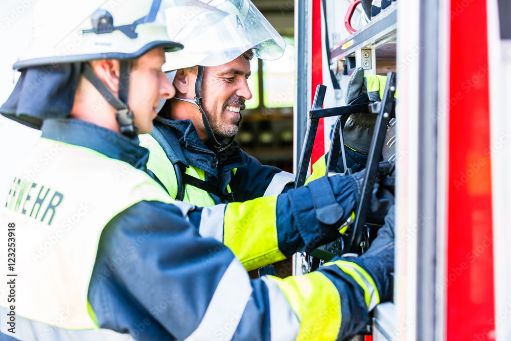 Fototapeta premium Feuerwehrleute schließen Schlauch an Einsatzfahrzeug an