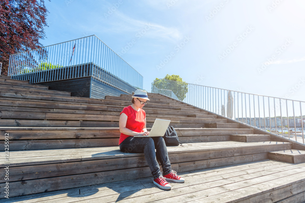 Girl working at laptop on the wooden stairs. Female freelancer