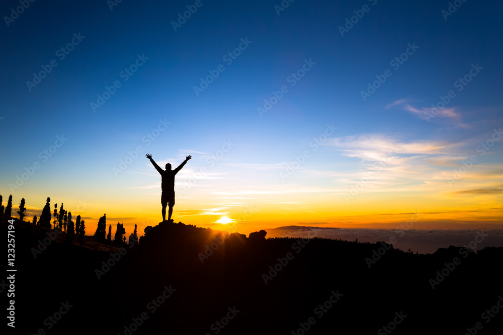 Man with arms outstretched celebrate mountains sunset
