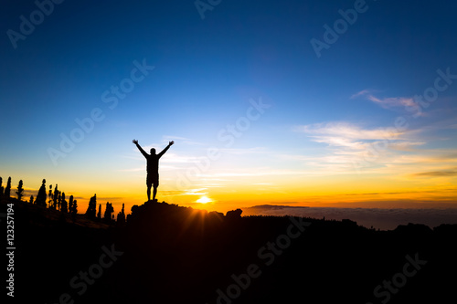Man with arms outstretched celebrate mountains sunset