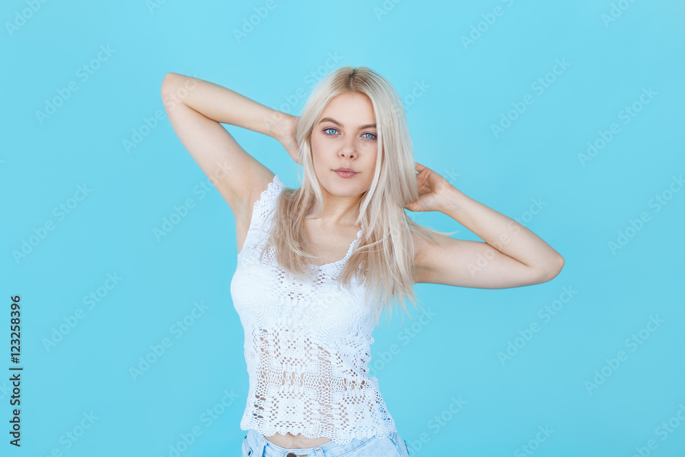young blond female in white clothes posing over blue background young blond female in white clothes posing over blue background