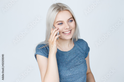 Young cute woman talking on phone over grey background