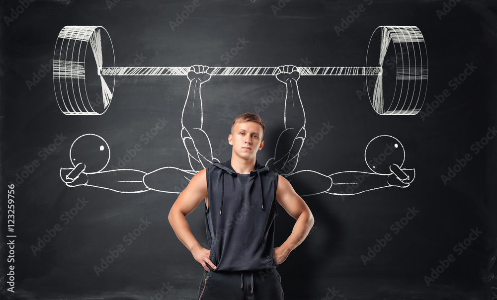 Athletic sportsman standing on the background with sketches of barbells and dumbbells.
