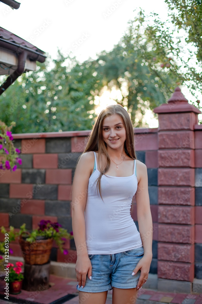 Smiling young brunette woman posing in yard of her residence in Smiling young brunette woman posing in yard of her residence in