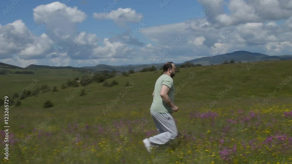 Camera panning following a man who is running over a field. Camera panning following a man who is running over a field.