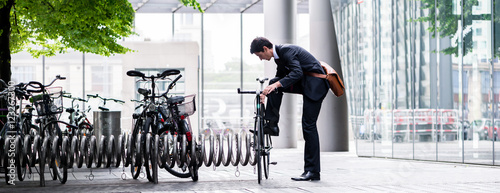 Businessman parking his bicycle in town photo