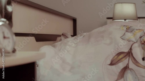 Annoyed young man lying in bed gets tired of noise and covers fully with blanket