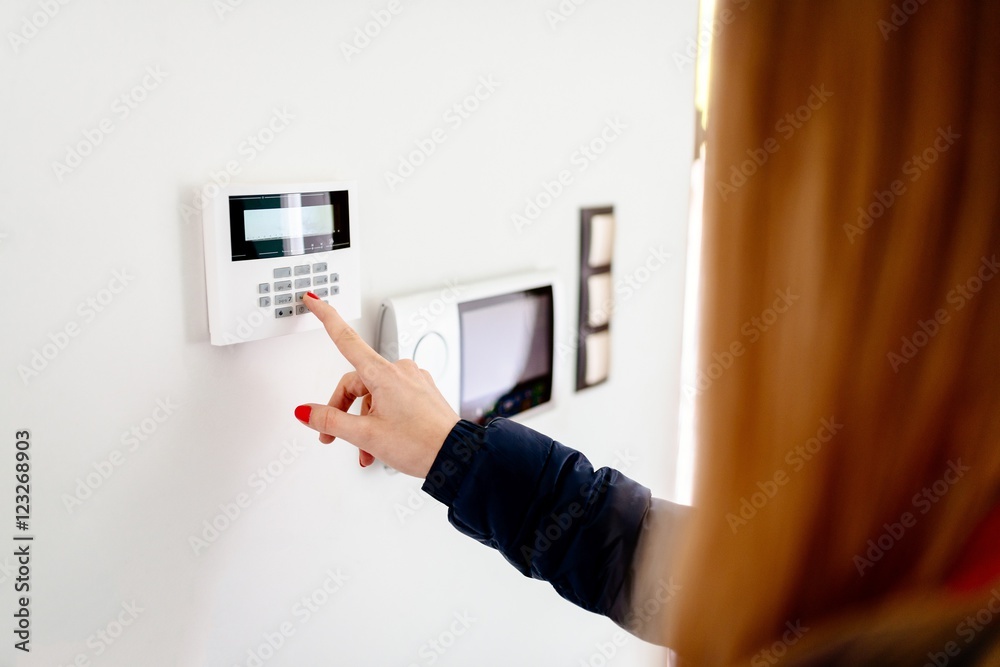Young woman entering security code on keypad