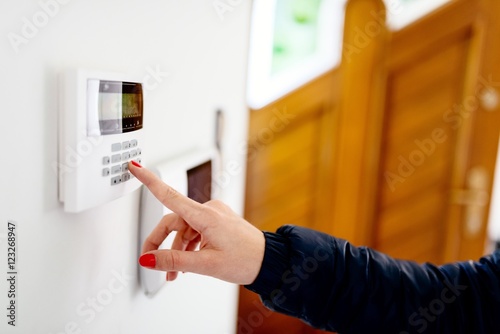 Young woman entering security code on keypad photo